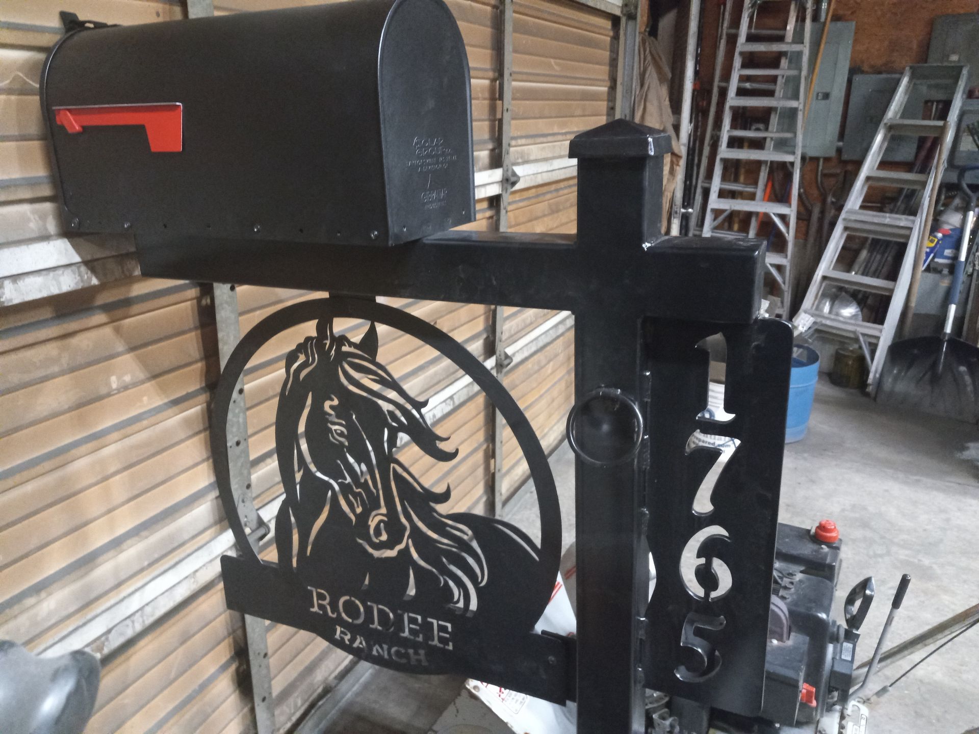 Black mailbox with horse art, address numbers, and 