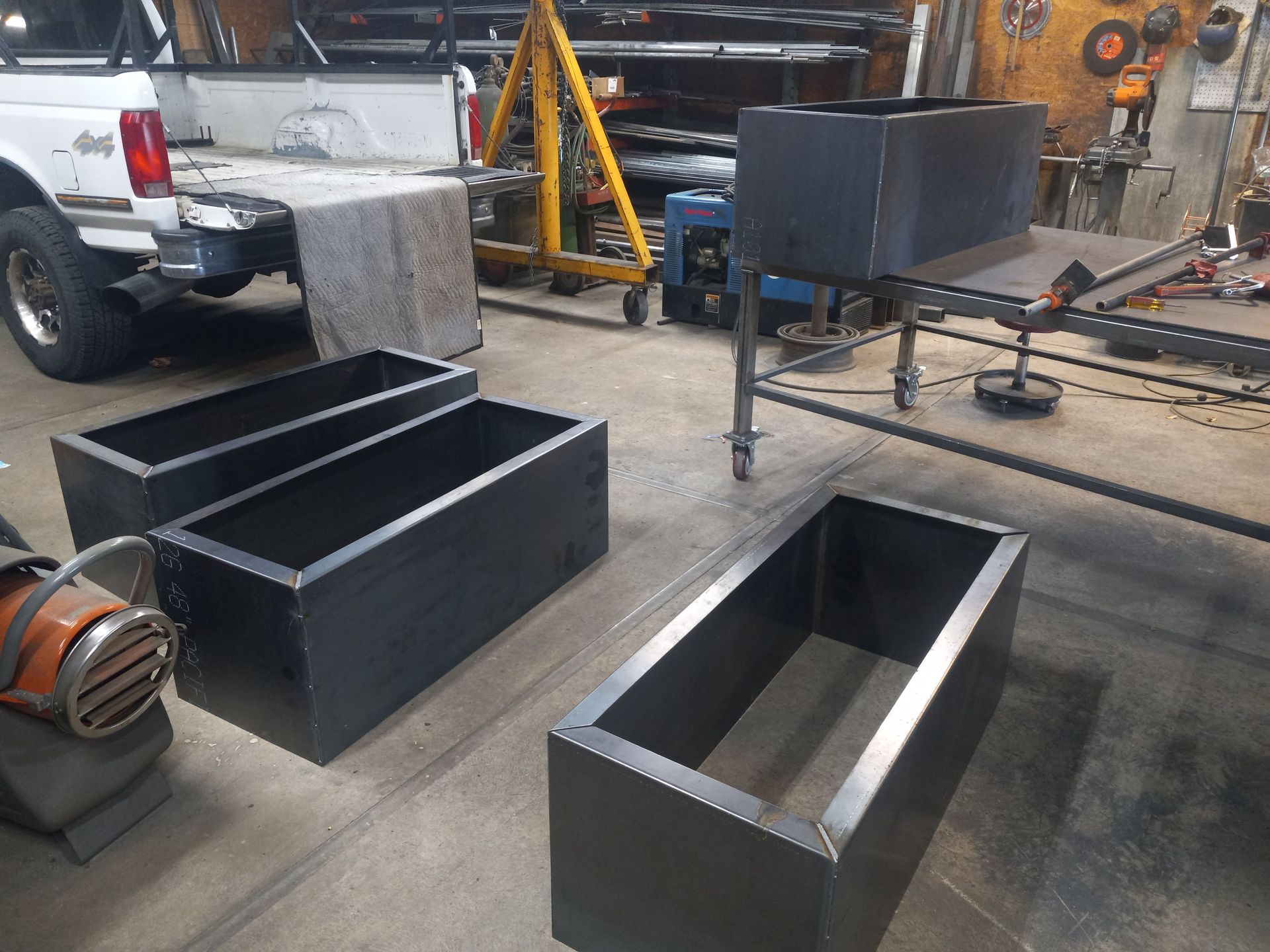 Metal rectangular planters in a workshop with tools and a truck.