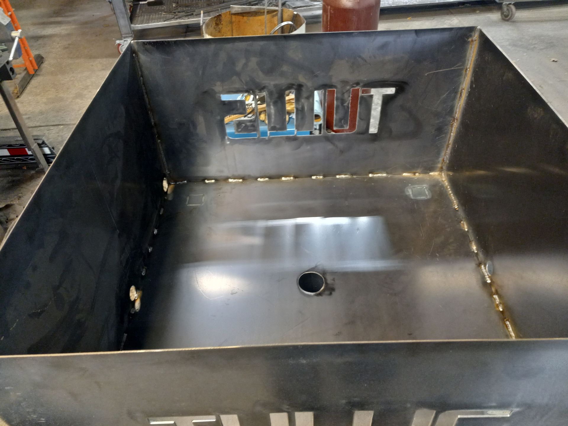 Black metal fire pit with welded seams and logo cutout.