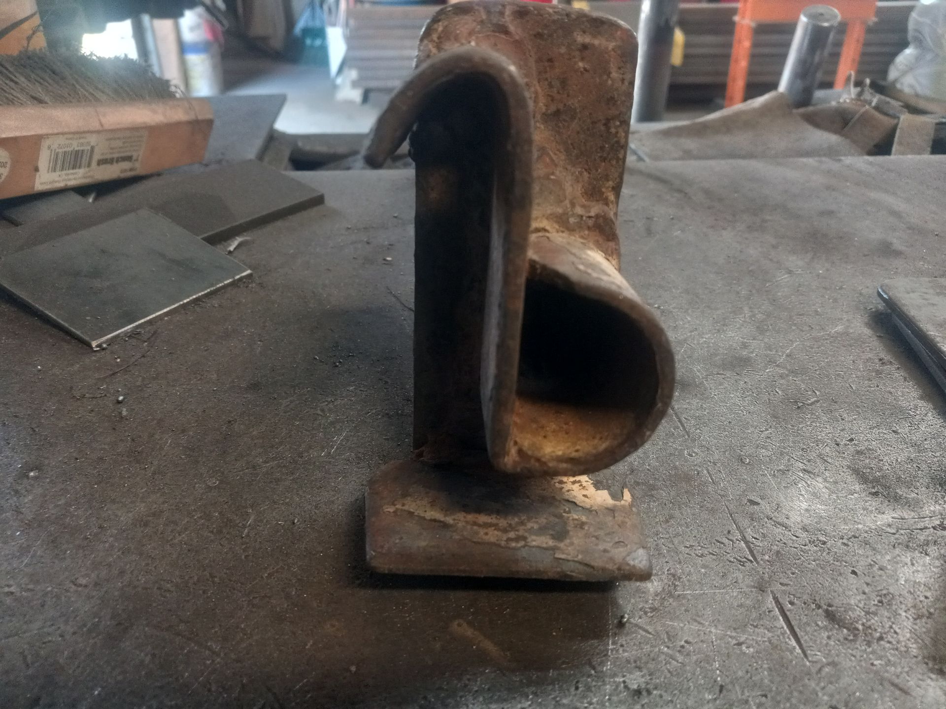 Rusty, U-shaped metal bracket on a dark workbench.