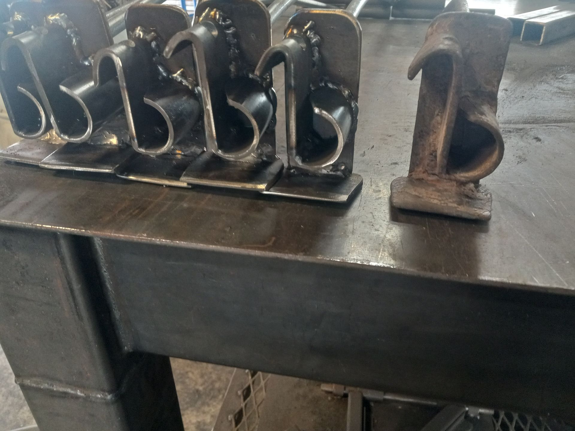 Metal welded pieces on a steel table, likely for industrial use.