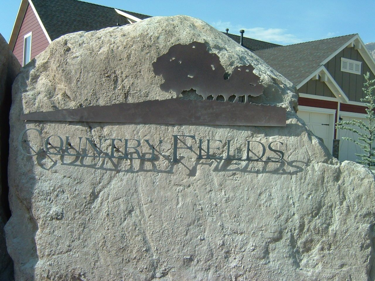 Large stone sign with metal lettering and oak tree silhouette reading 