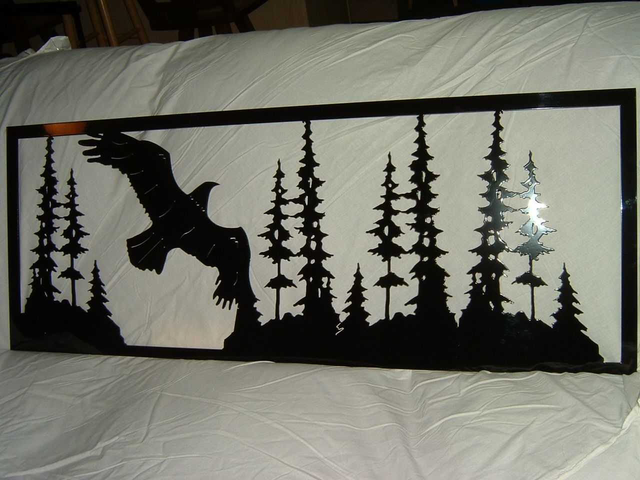 Black metal art: an eagle flies over a forest silhouette against a white background.