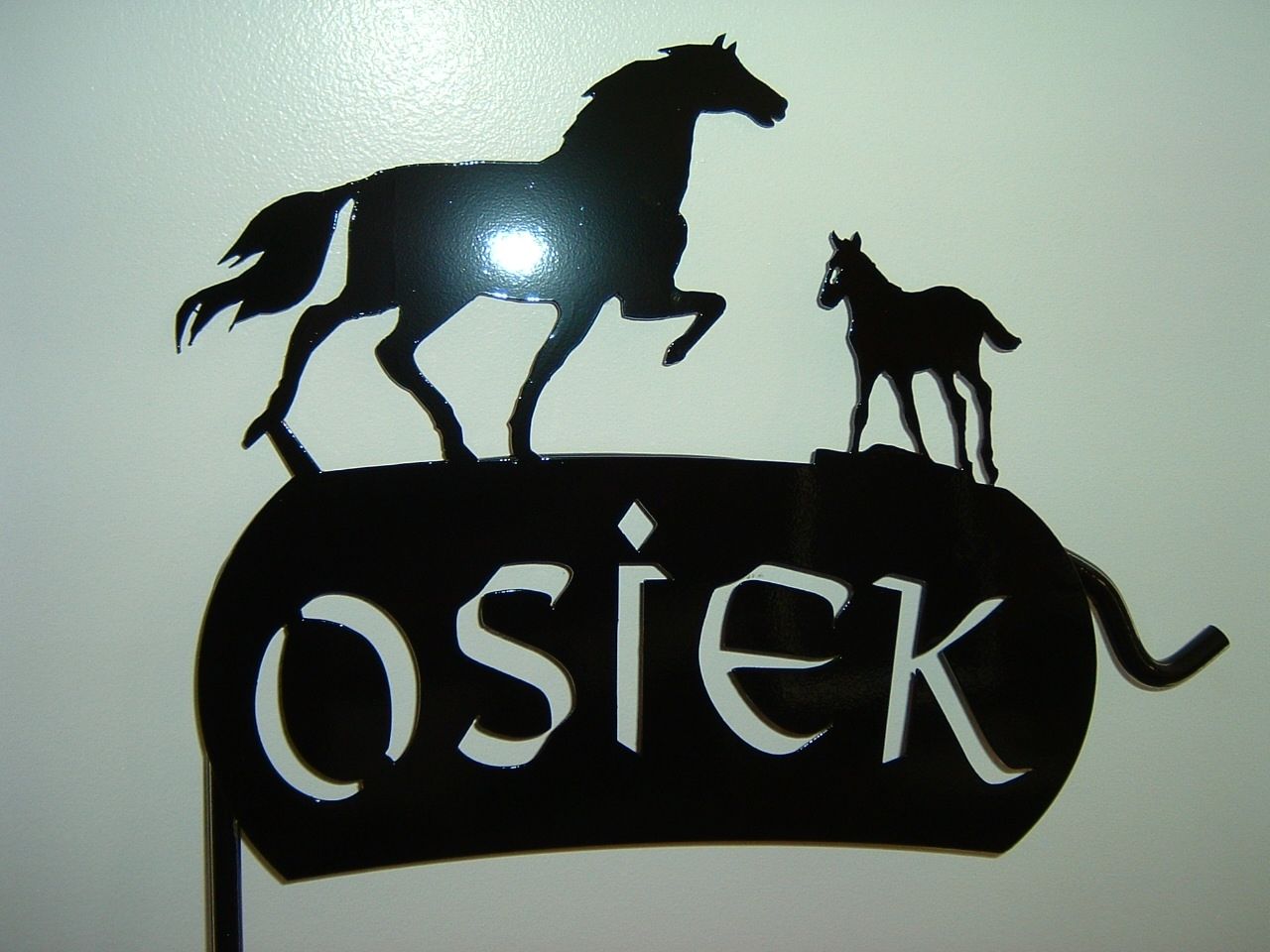 Black metal sign with two horses and the name 