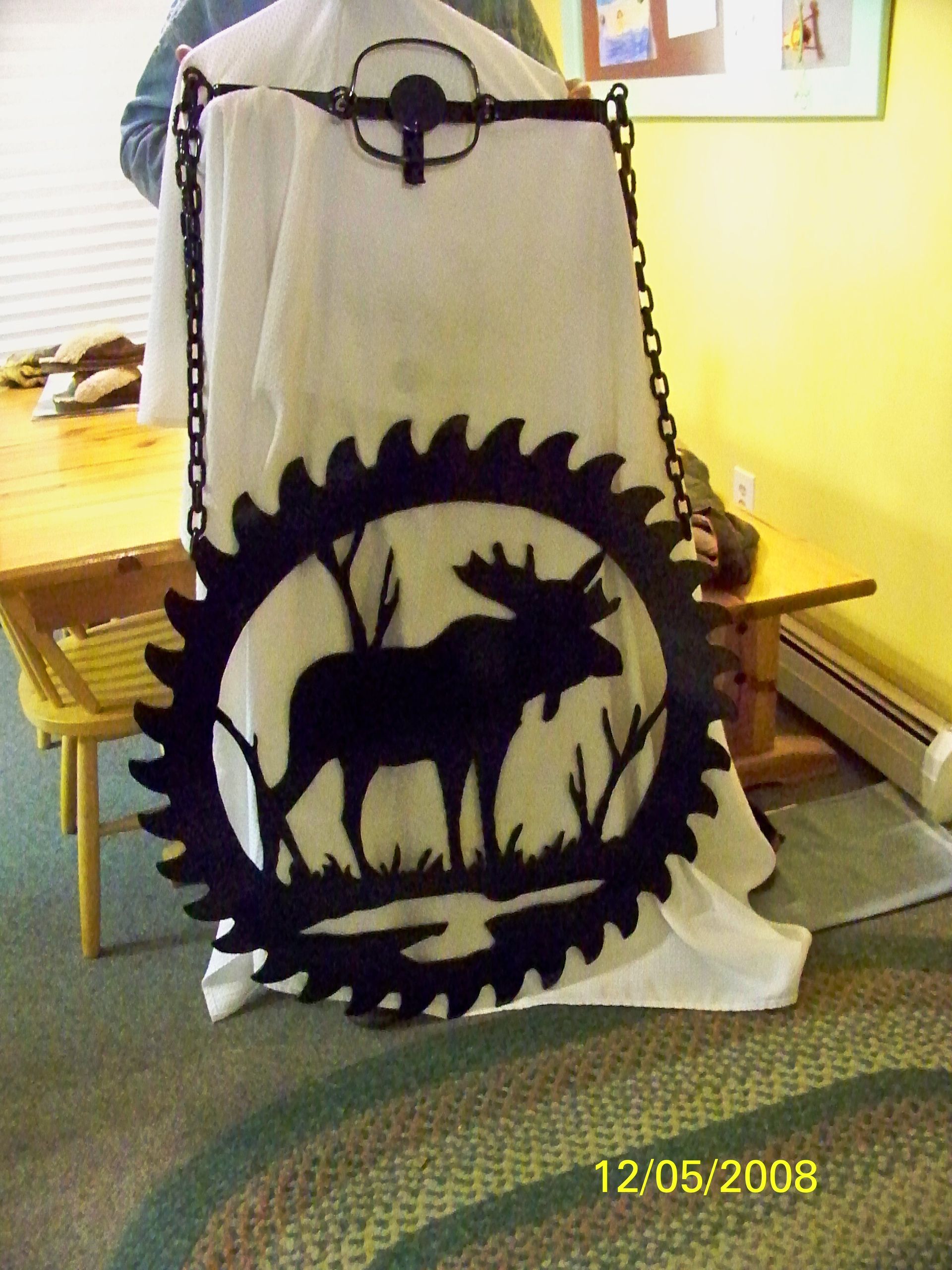 Black metal moose silhouette artwork hanging by chains.