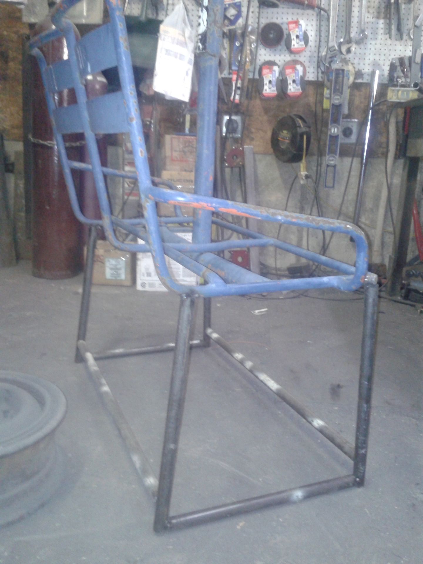 Blue metal chair frame in a workshop setting.