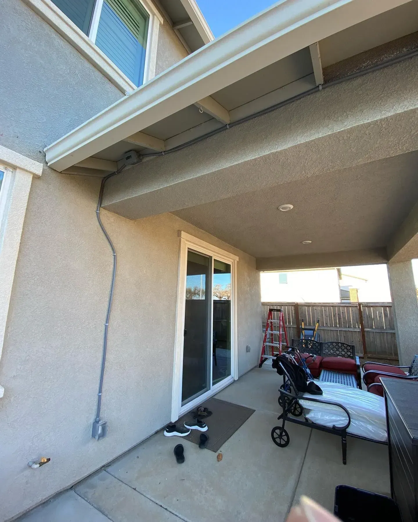 Patio with sliding glass door, covered by an overhang, and outdoor furniture.