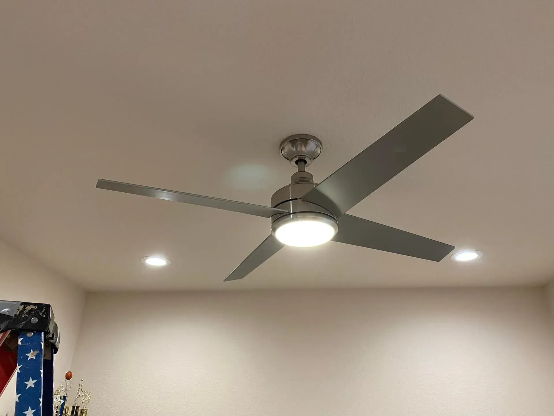 Ceiling fan with light fixture against a white ceiling. Two recessed lights are visible.