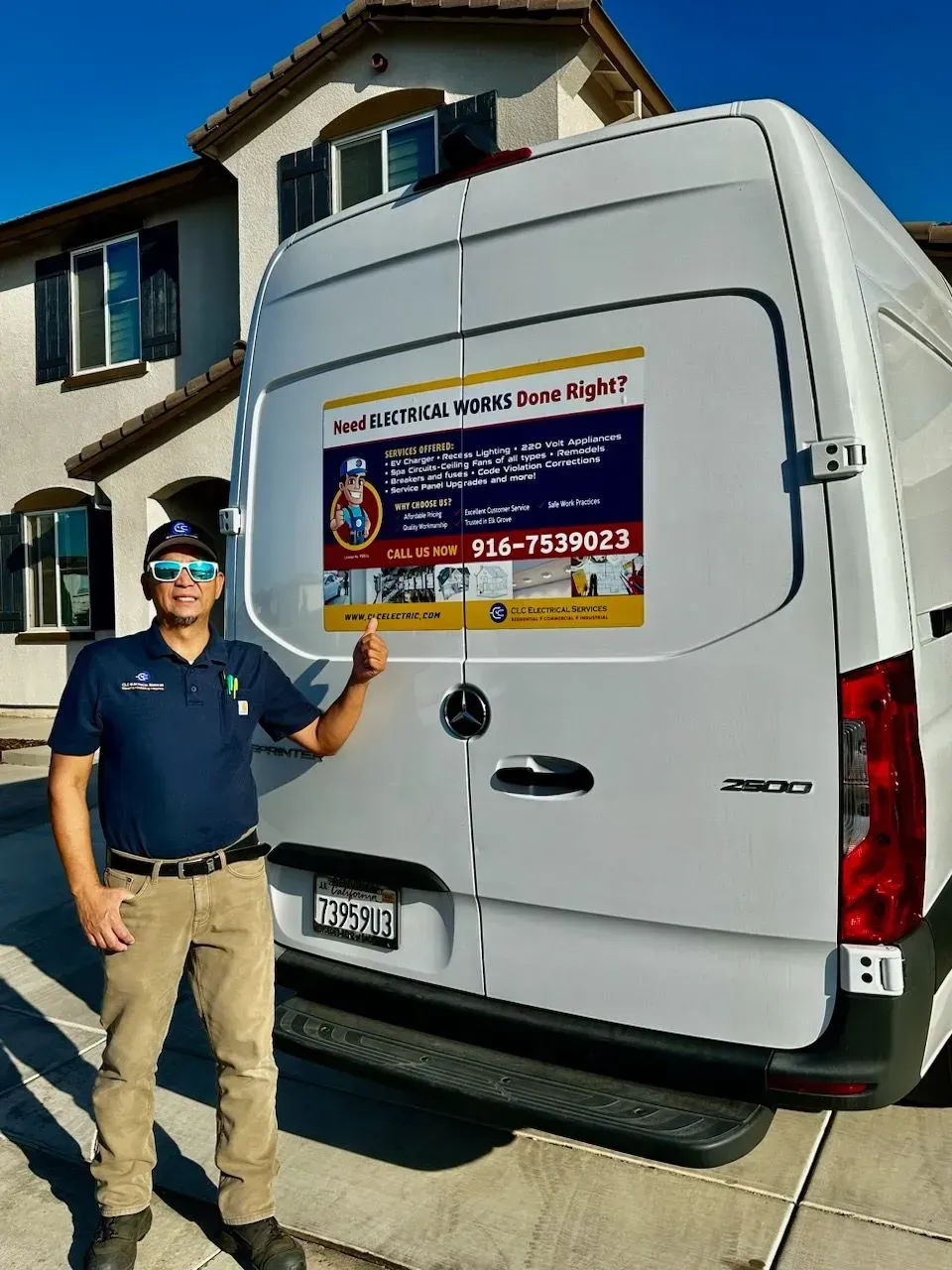 Man in uniform gives thumbs up next to a white service van in front of a house.