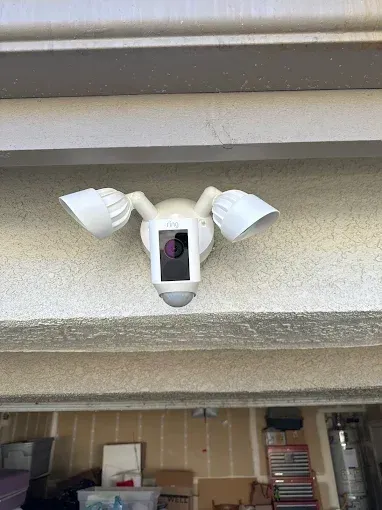 White Ring floodlight camera mounted under a building overhang.
