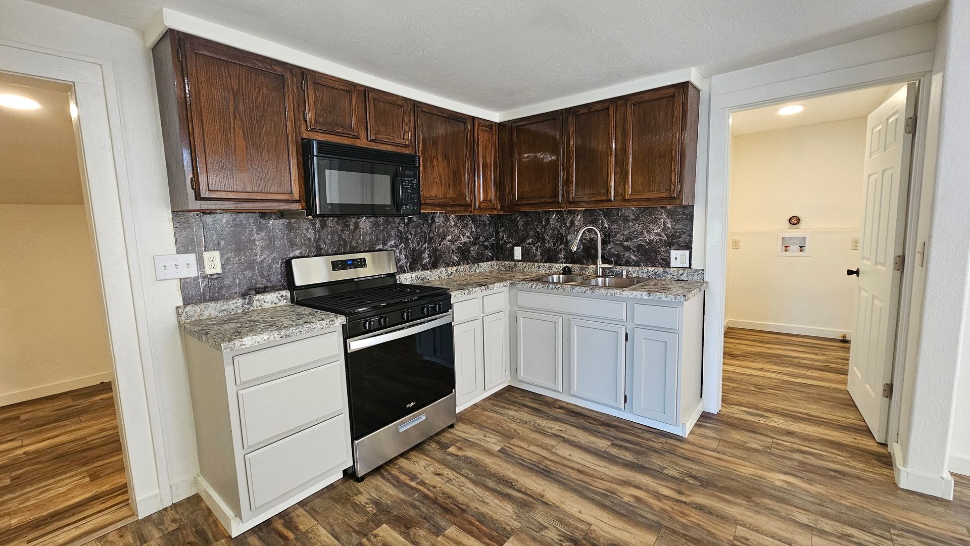 Kitchen with dark brown cabinets, stainless steel appliances, and white countertops and cabinets, and a door on the right.