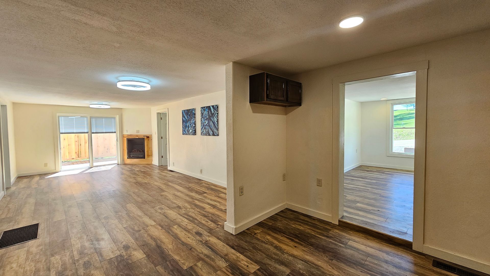 Open living room with wood flooring, fireplace, and doorway to a bedroom.