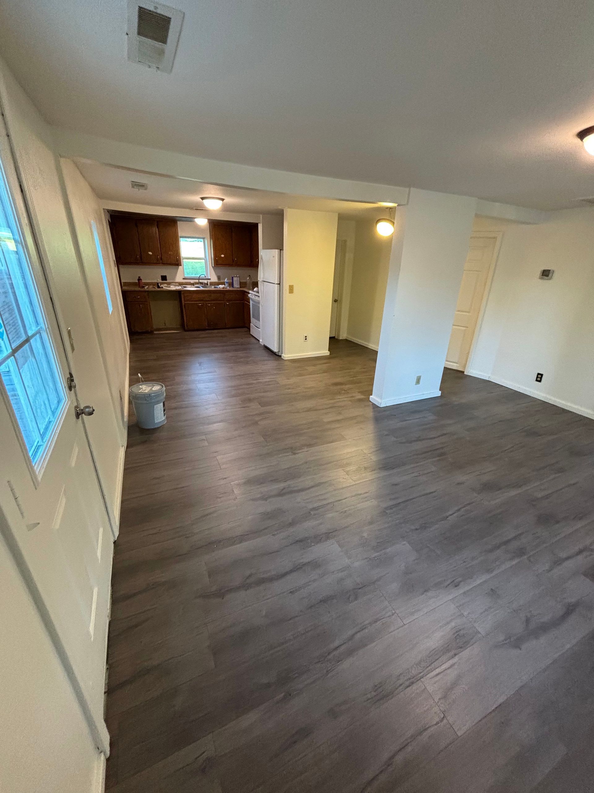 Interior view of a newly renovated space with wood-look flooring leading to the kitchen.
