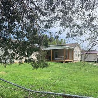 A house with a screened in porch is sitting on top of a lush green field.
