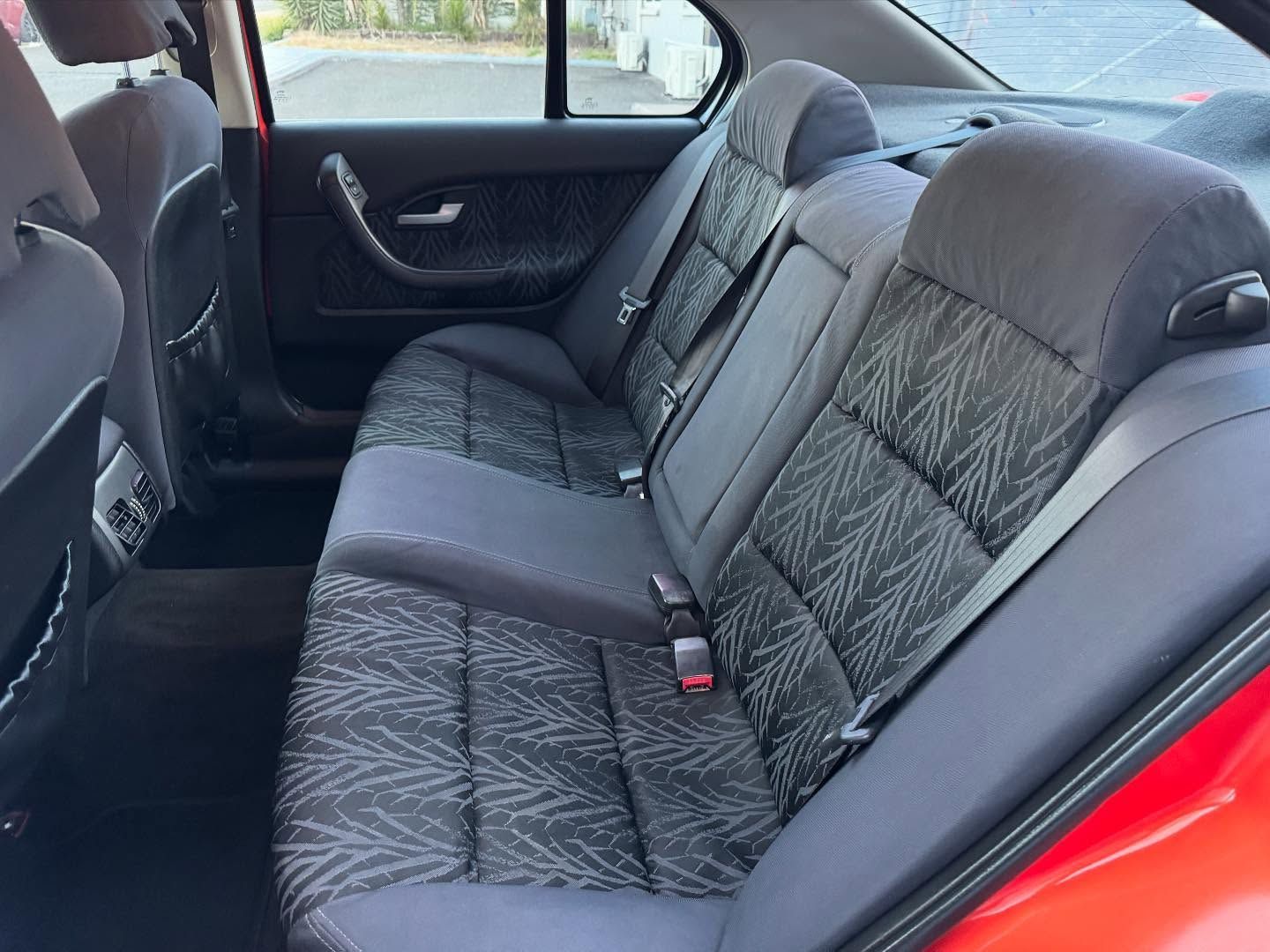 Back Seat of a Red Car With Gray Patterned Upholstery, Headrests, and Seatbelts — Oliver's Hand Car Wash in Norville, QLD