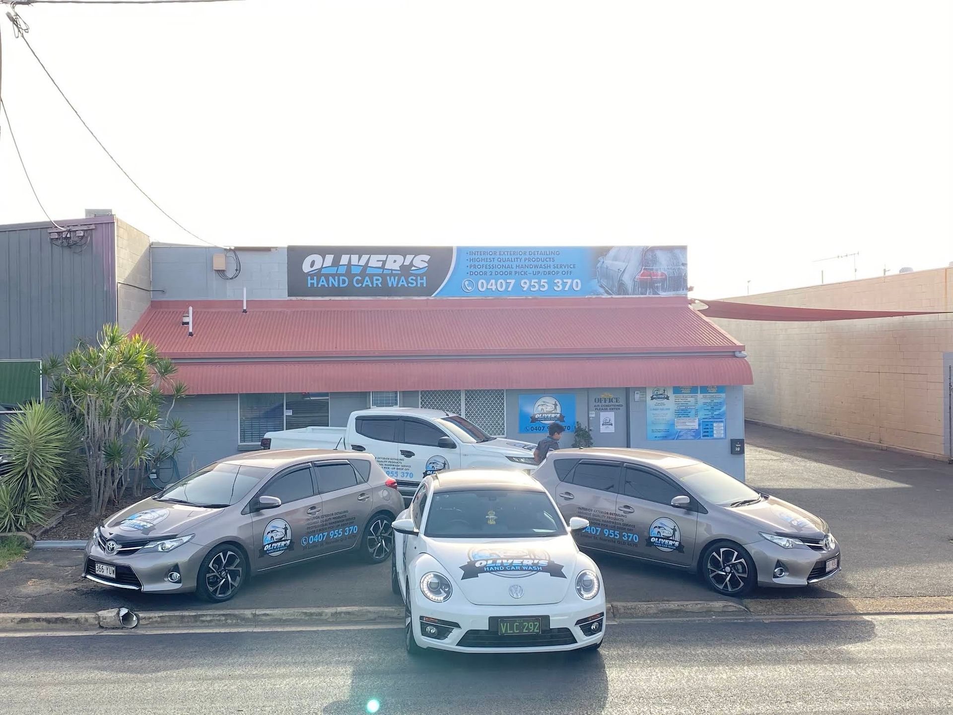 Cars Parked in Front of a Building With a Business Sign — Oliver's Hand Car Wash in Norville, QLD