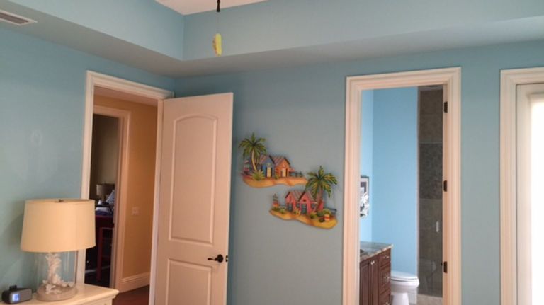 A bedroom with blue walls , white doors , a lamp , and a bathroom.