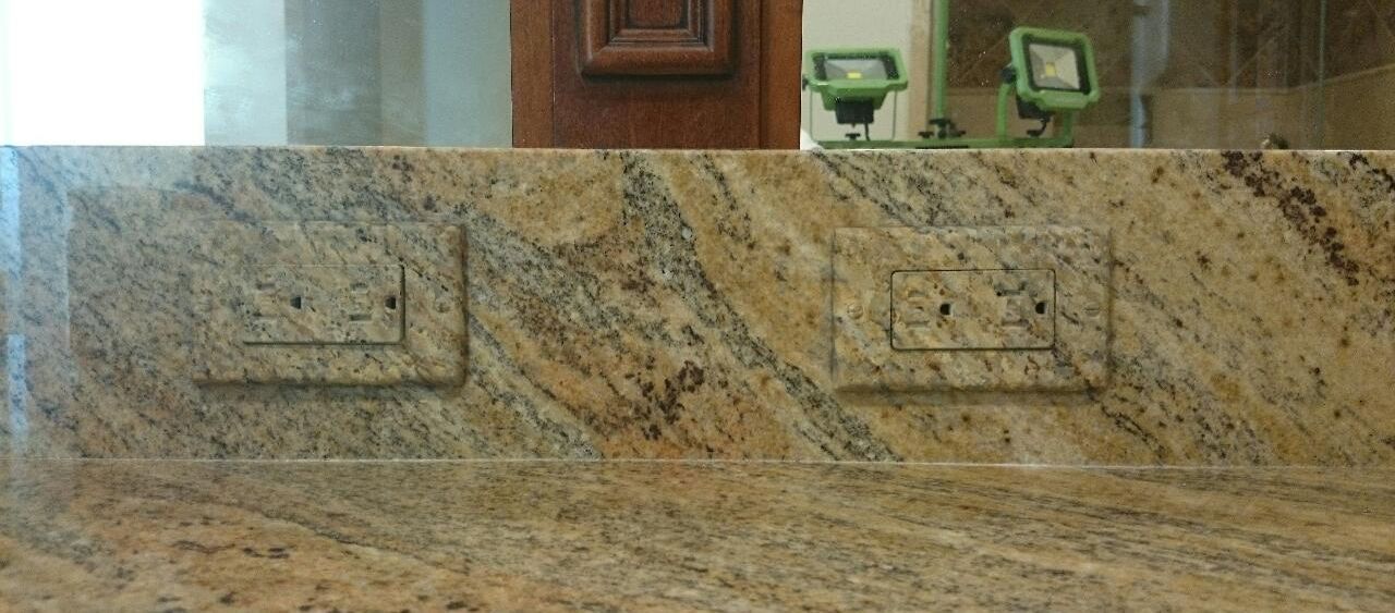 A bathroom sink with a granite counter top and a mirror.