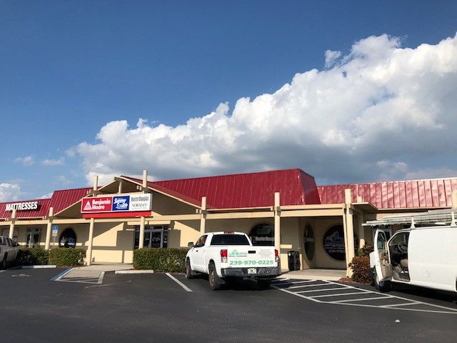 A white truck is parked in front of a building with a red roof.