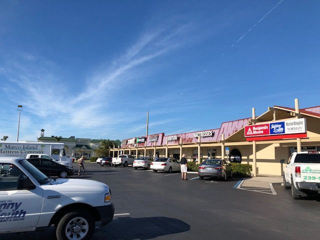 A white truck is parked in a parking lot in front of a store.