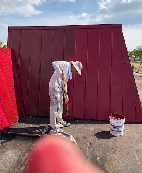 A man is painting a red wall with a brush.