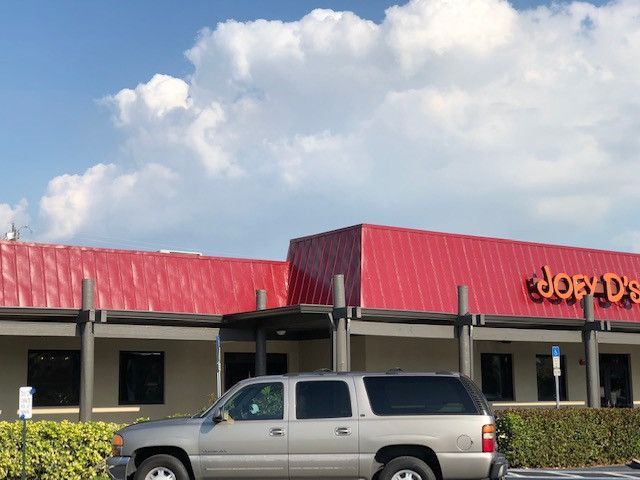 A silver suv is parked in front of a job 's restaurant