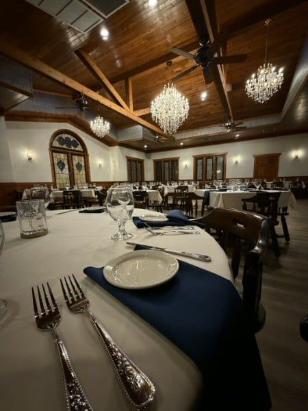 Elegant restaurant interior with round tables, white tablecloths, and chandeliers.