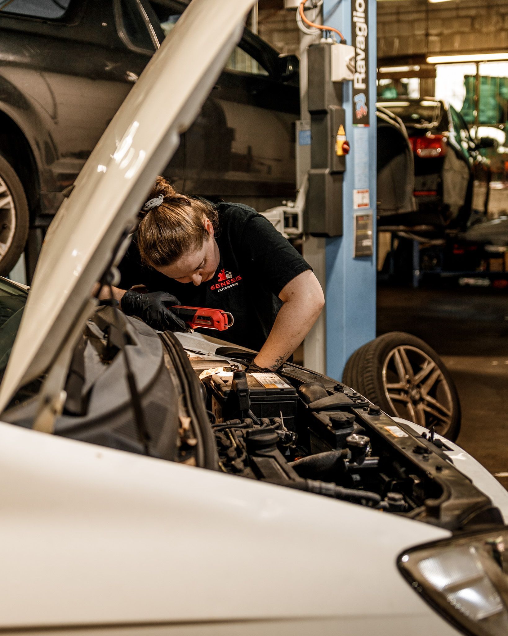 a woman is working on the engine of a car in a garage .