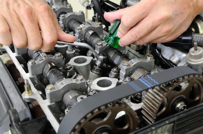 a person is working on a car engine with a wrench .