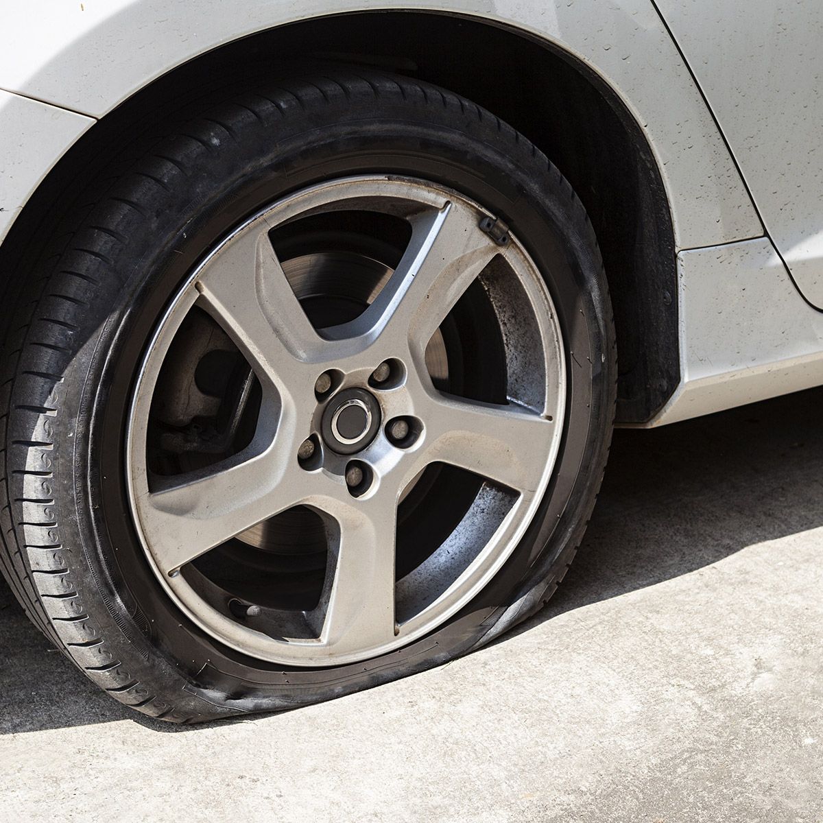 a silver car with a flat tire on the side