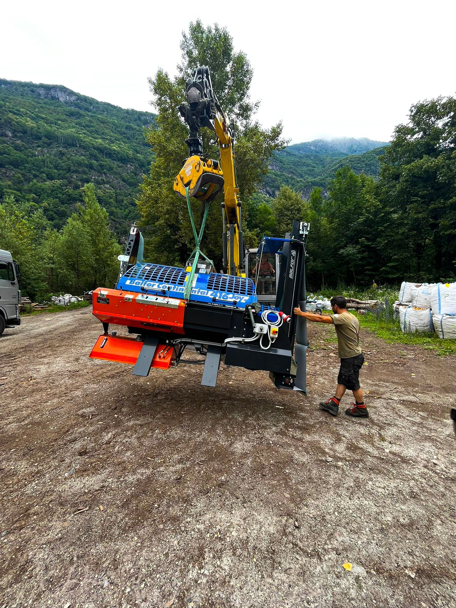 Un uomo è in piedi accanto a un carrello elevatore in un campo sterrato.
