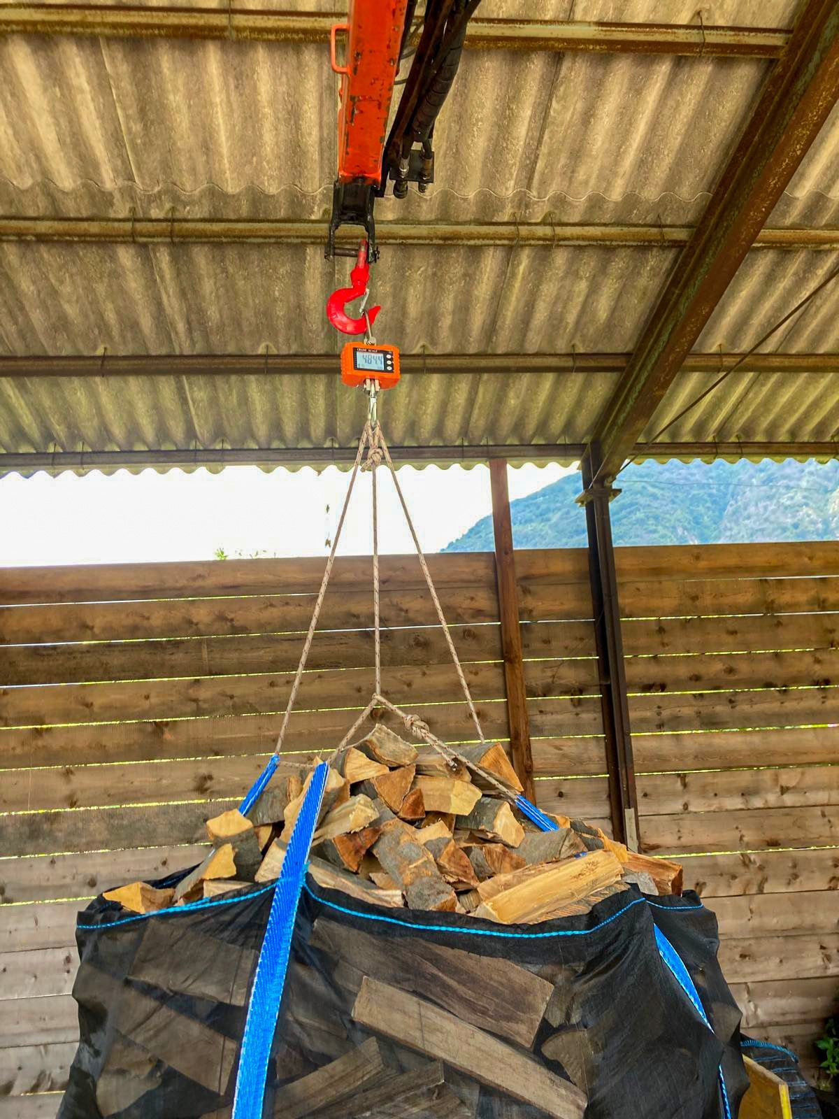 Un sacco di legna viene sollevato da una gru.