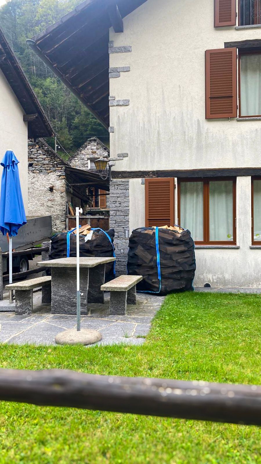 Davanti a una casa c'è una grande catasta di legna.