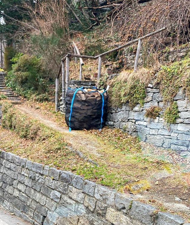 Un grande sacco di legna è legato ad un muro di pietra.