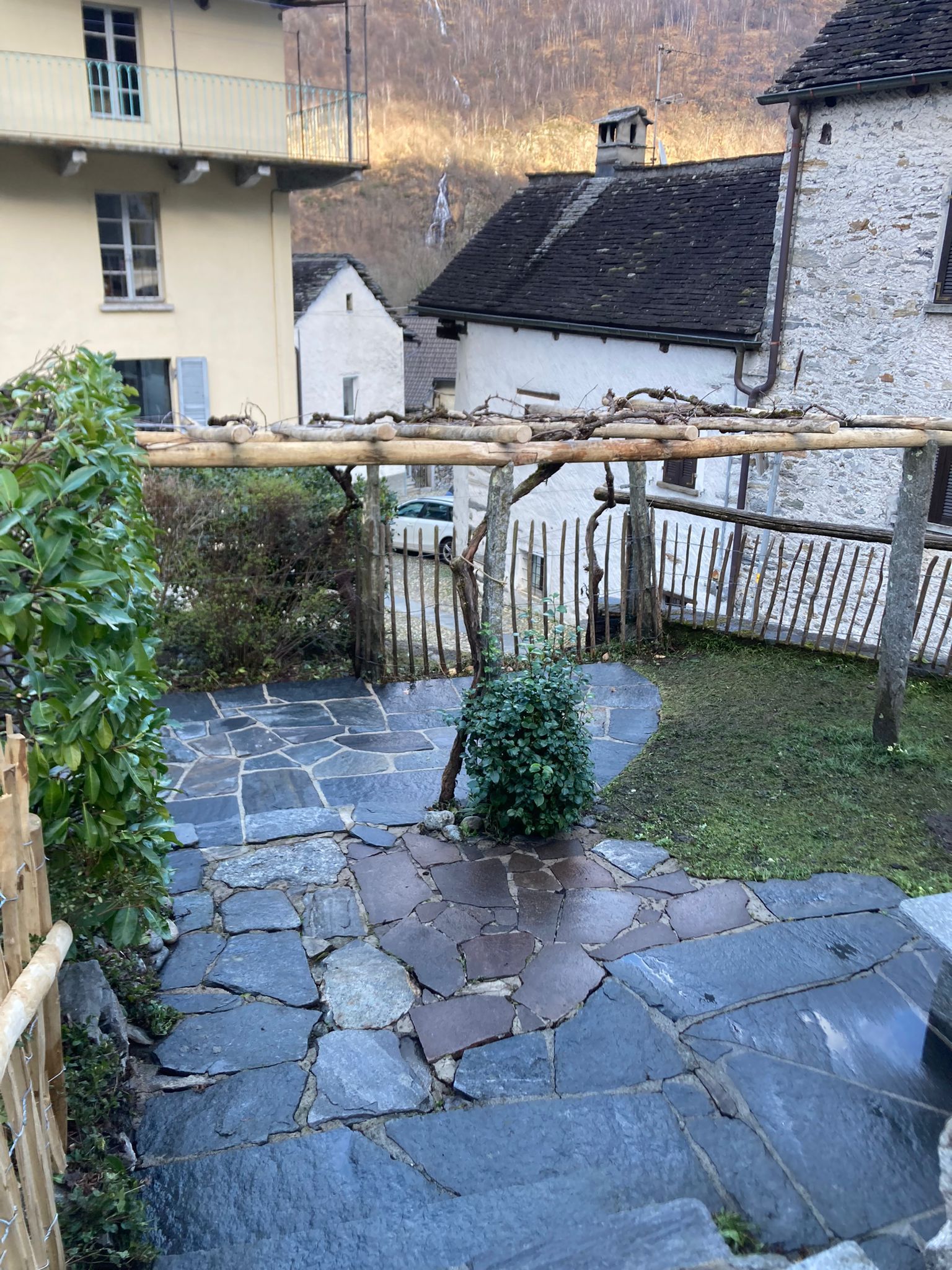 Un patio in pietra con staccionata in legno davanti a una casa.