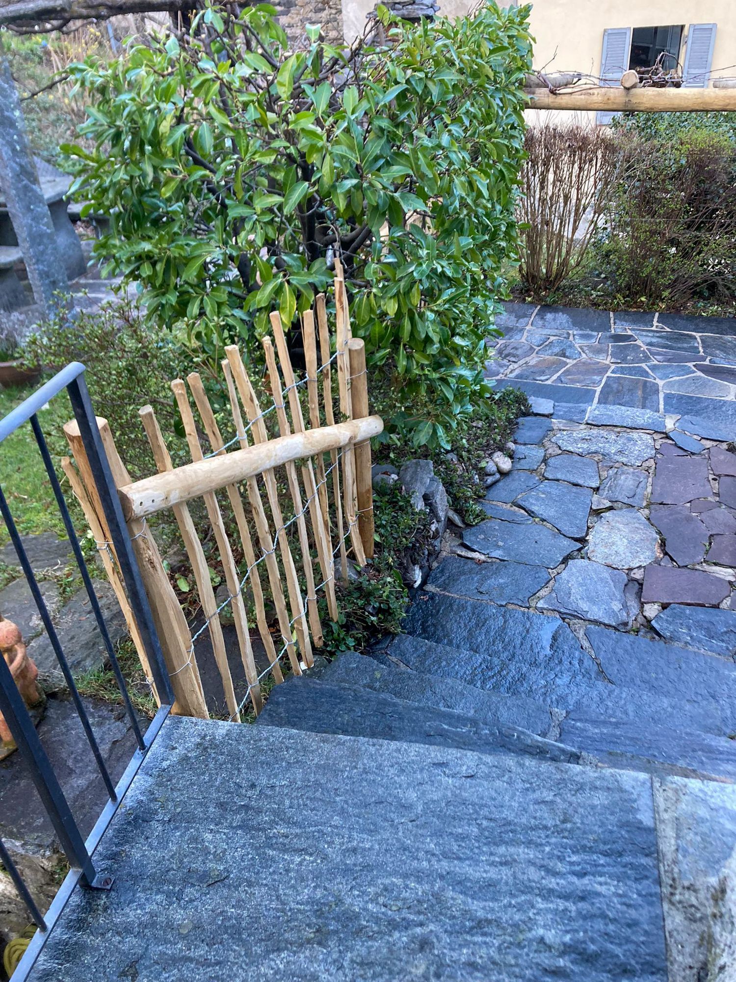 Una staccionata in legno circonda una serie di scale che conducono ad una passerella in pietra.