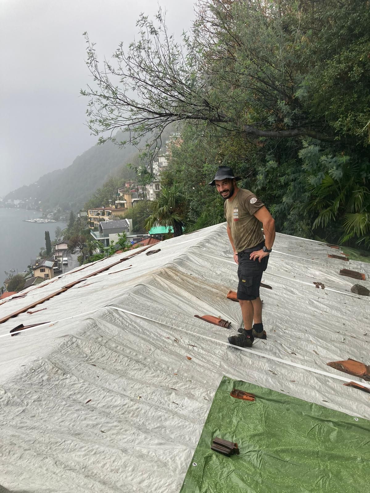 Un uomo è in piedi sopra un tetto ricoperto di plastica.