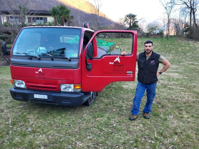 Un uomo è in piedi davanti a un camion rosso con le porte aperte.