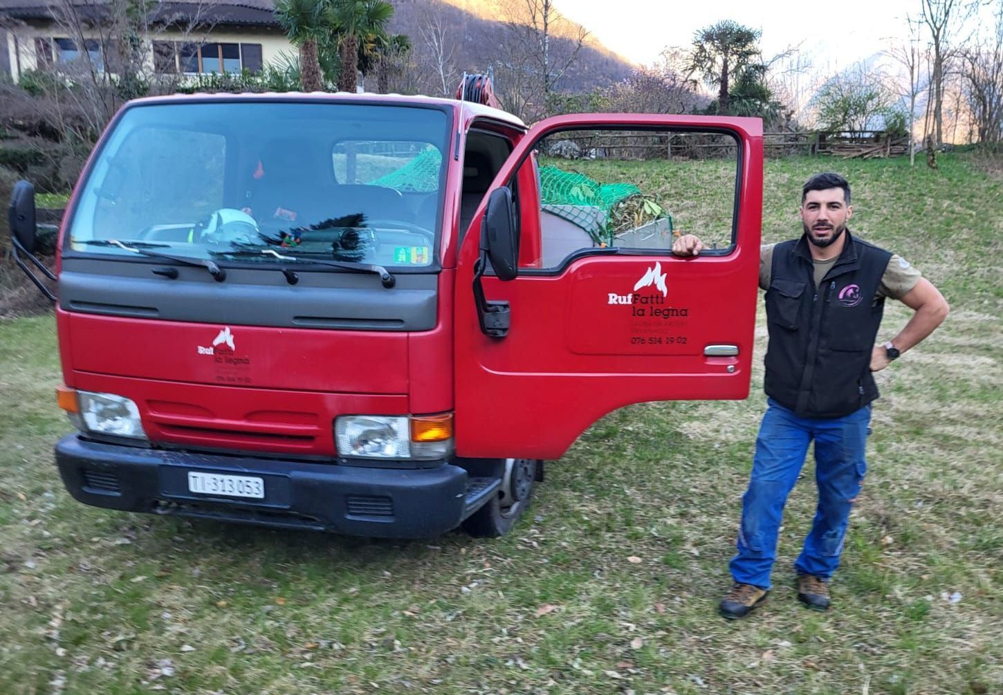 Un uomo in piedi davanti a un camion rosso con la portiera aperta