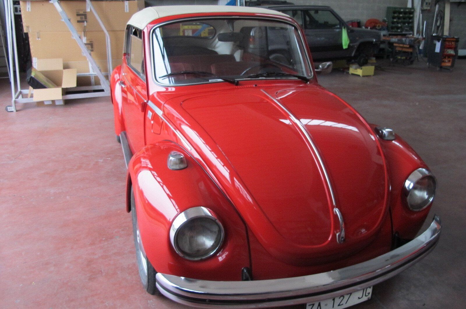 Un Maggiolino Volkswagen decappottabile rosso d'epoca in un garage.