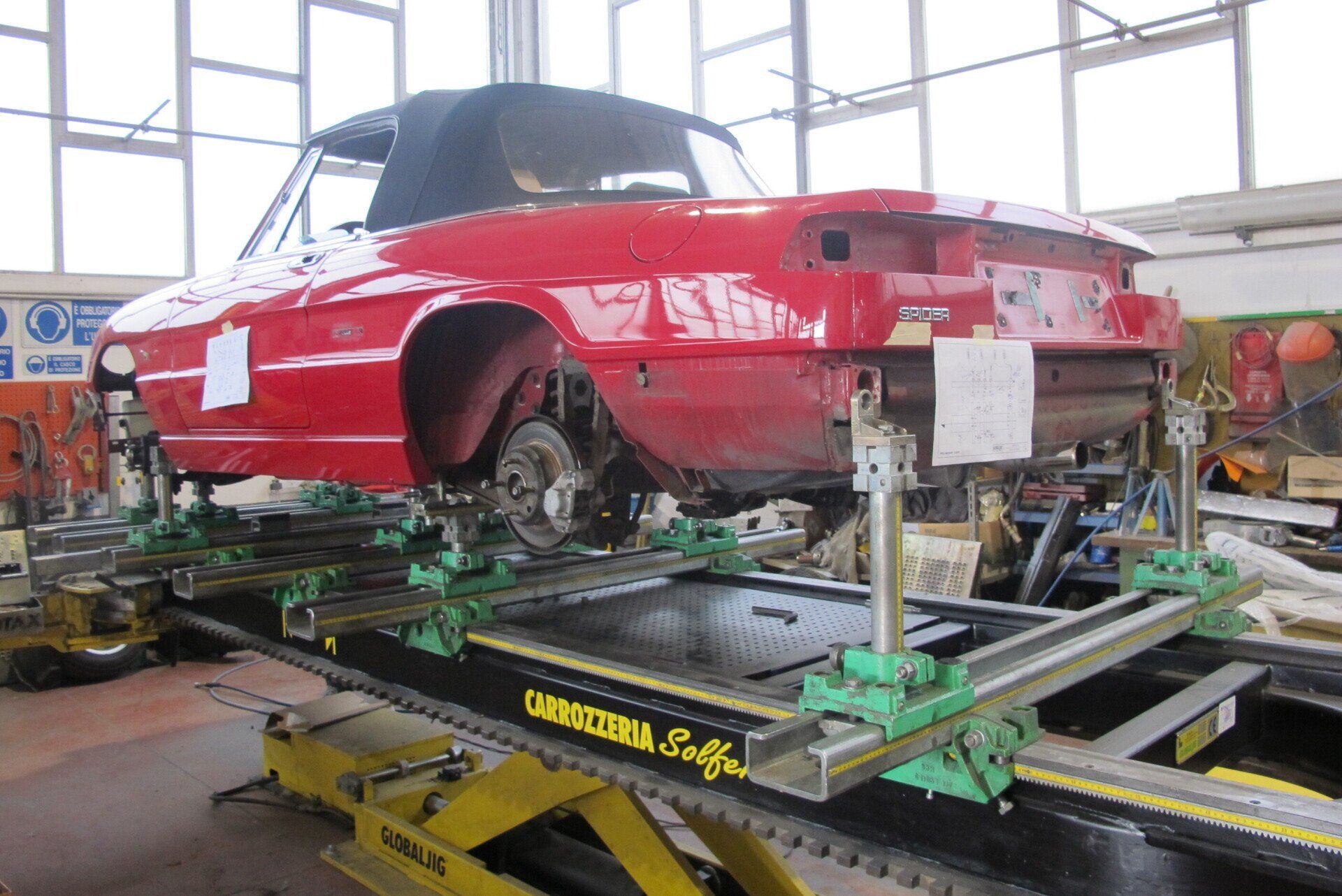 Una decappottabile rossa montata su una macchina per l'allineamento delle ruote in un'officina.