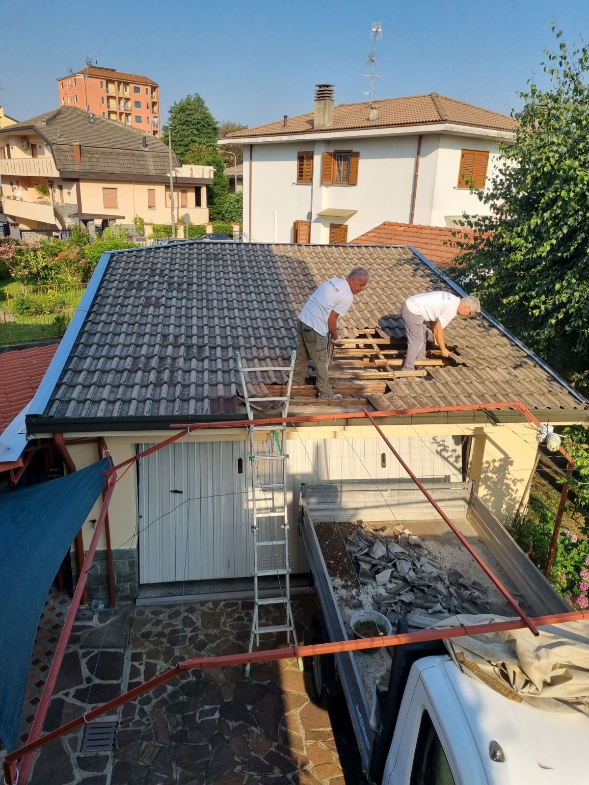 Edificio in fase di ristrutturazione, ricoperto da una rete verde, con lo skyline della città sullo sfondo.