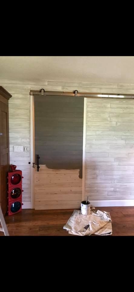 Barn door being painted; wood floor; light gray walls.