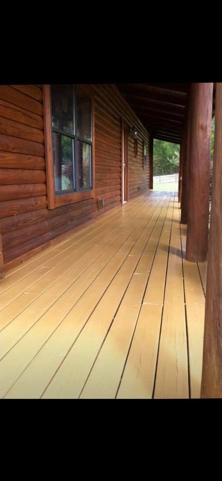 Wooden porch with a log cabin, sunny day.