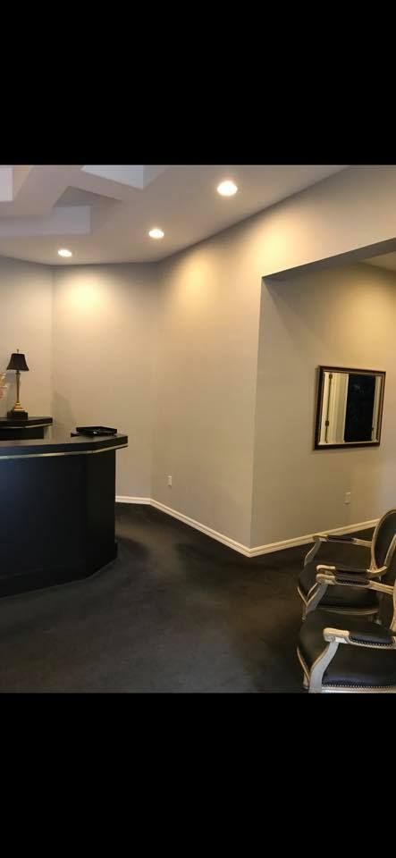 Reception area with a black counter, dark floor, recessed lighting, and a mirror on the wall.
