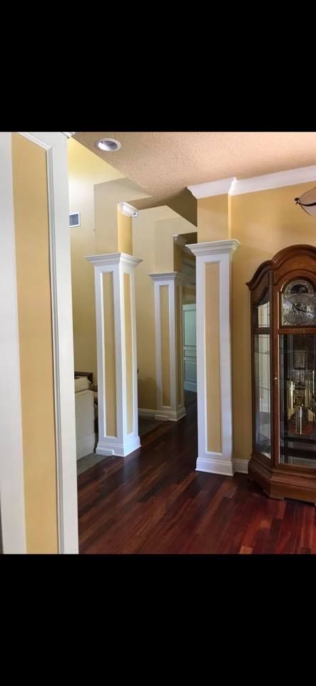 Interior with hardwood floors, columns, and a grandfather clock.