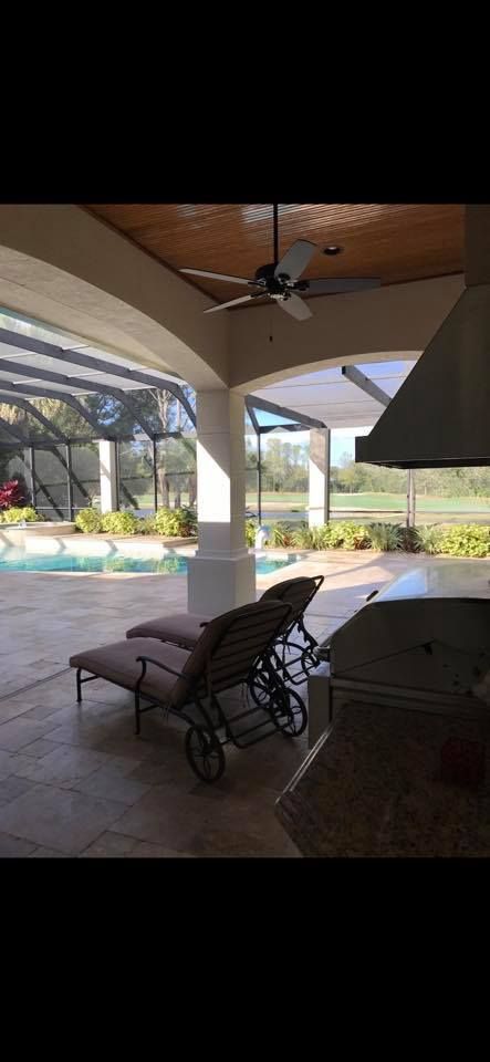 Patio with pool view: lounge chairs, screened enclosure, ceiling fan, and outdoor kitchen.