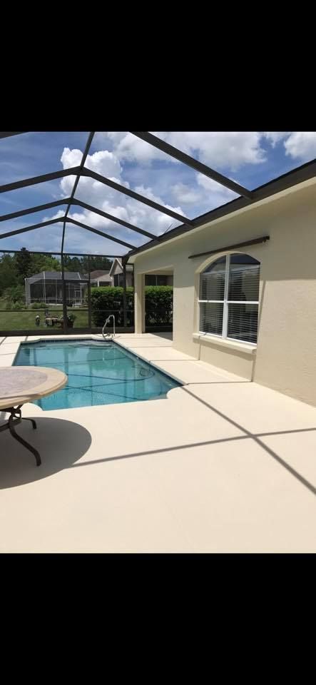 A sunny backyard with a pool and a screened enclosure, house visible in the background.