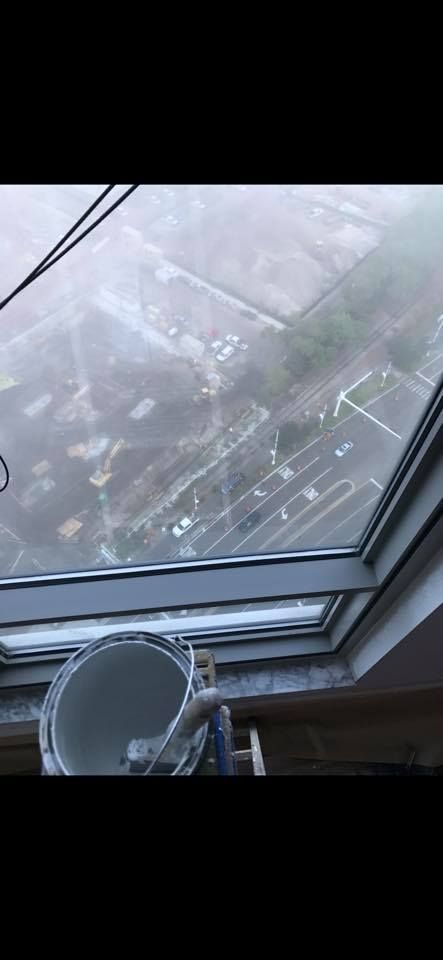 View from a window with a paint bucket, looking over a foggy landscape with buildings and roads.