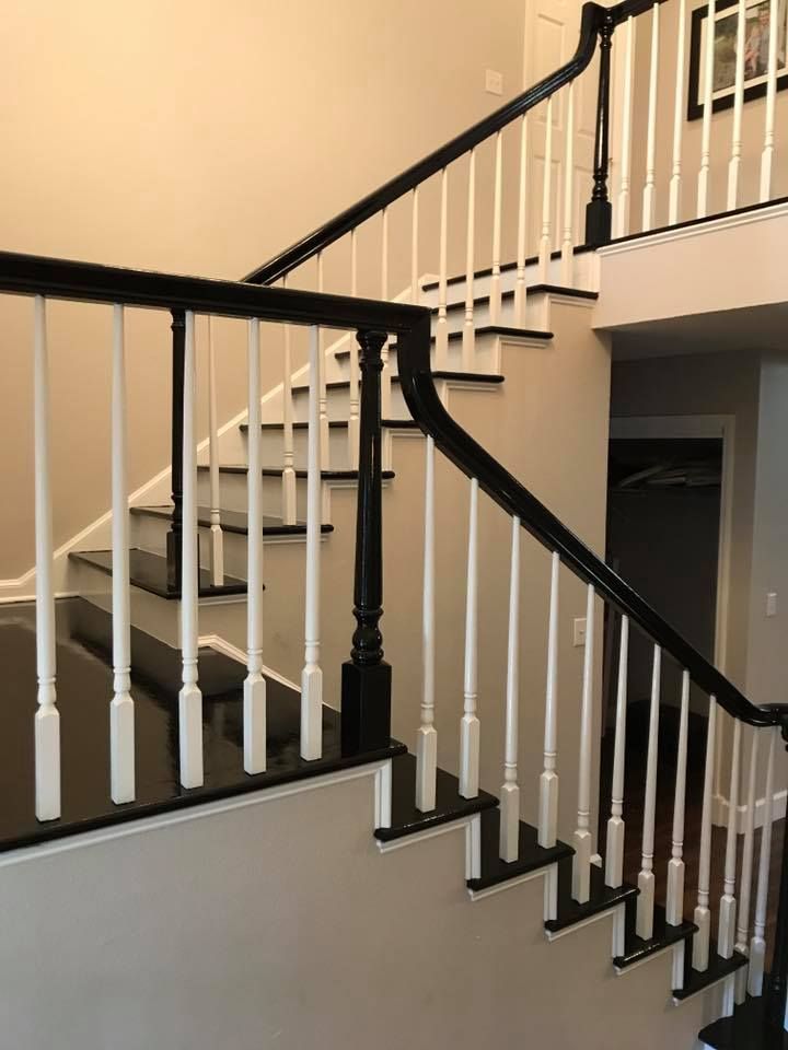 Staircase with black railings and white balusters. Black treads and white risers. Beige walls.